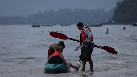 assisting tourists with kayak on krabi shore