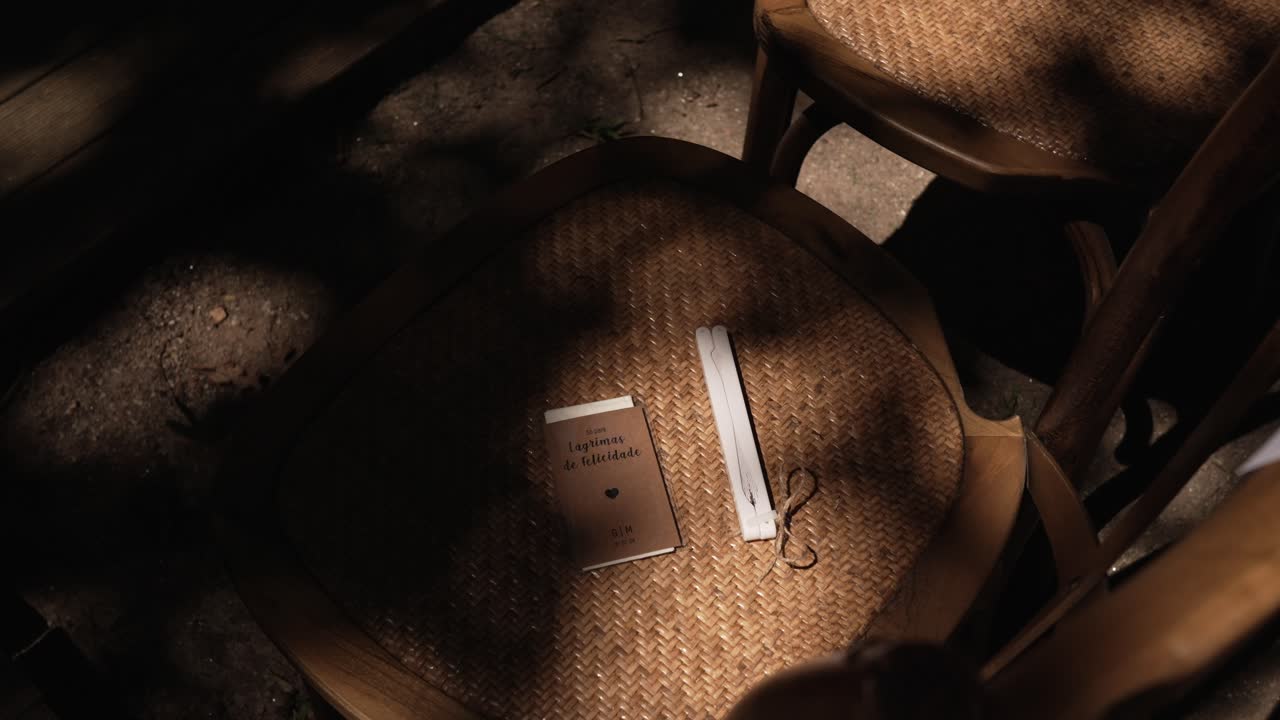 Wooden wedding chair with a booklet and handkerchief placed under soft shadows