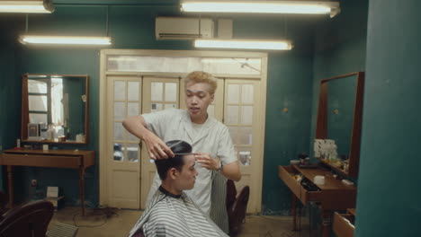 asian barber giving haircut and talking to male client
