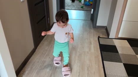 happy baby boy put on mom's slippers and walks in them by the room. adorable child plays at home. top view.