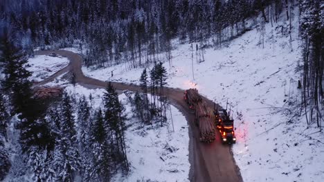 camera quickly moves forward towards loaded 18 wheeler hauling timber on dirt roads in snow covered winter logging camp in northern forest