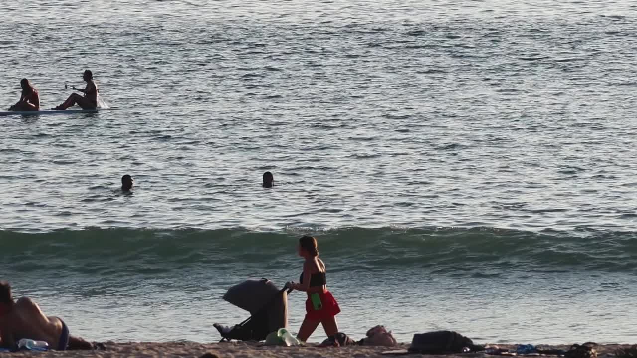 People enjoying the ocean waves and relaxing on the sandy beach under the sun.
