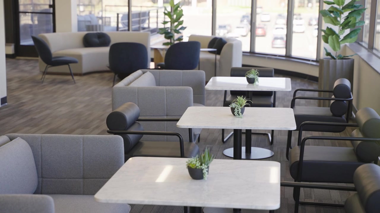 Spacious office lounge area featuring elegant sofas, marble tables, and greenery.