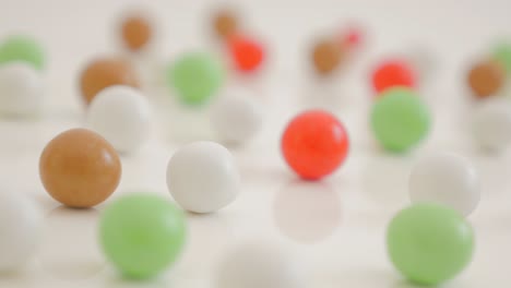 round shaped bonbons arranged on white reflective background 4k 2160p ultrahd footage - shiny candies on white surface with one red focused 4k 3840x2160 uhd video