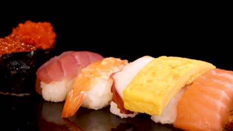 a vibrant assortment of nigiri and sashimi sushi rotates smoothly on a glossy black surface under bright, even lighting, highlighting fresh seafood textures
