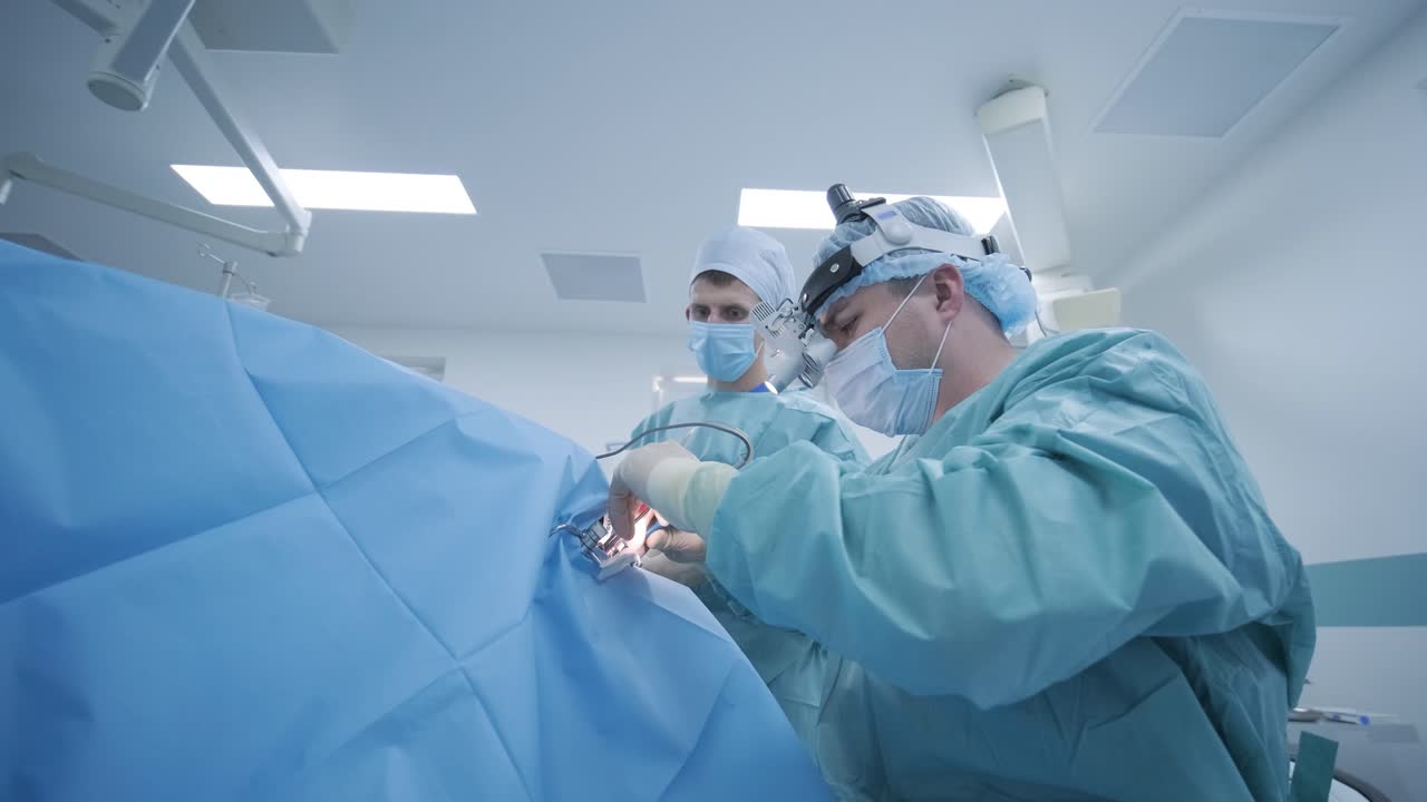 operación de extirpación de amígdalas, amigdalectomía bajo anestesia profunda, utilizando los últimos dispositivos, método de plasma frío, cortes hinchazón en la garganta, el médico trabaja con una nueva sonda, lámpara frontal médica, lupas quirúrgicas