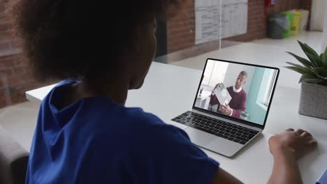 Back-view-of-african-american-woman-having-a-video-call-with-male-colleague-on-laptop-at-office