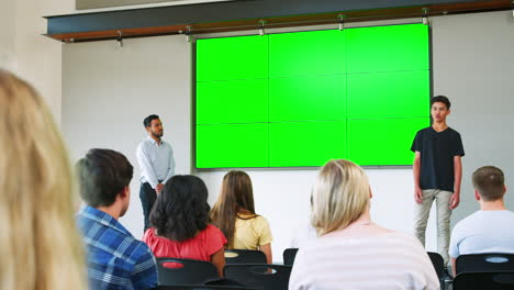 male student giving presentation to high school class in front of screen