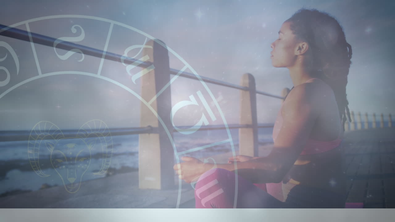 Animation of zodiac signs with young african woman meditating on pier at beach