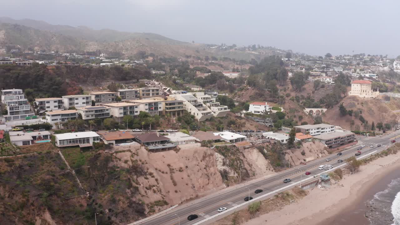 Aerial low dolly shot along Pacific Coast Highway near the Sunset Mesa and Castellammare neighborhoods after the Palisades Fire in Malibu, California. 4K