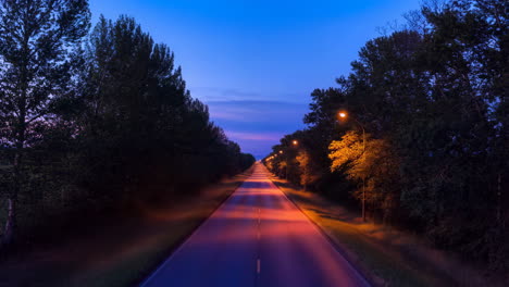long straight road lined with trees at twilight