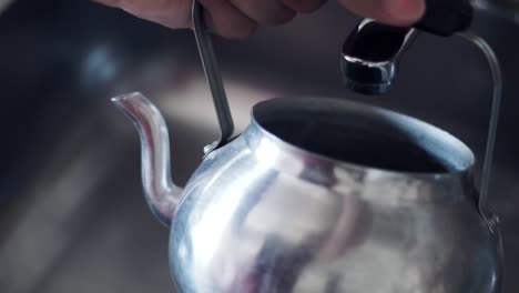 pouring water into the kettle to prepare tea