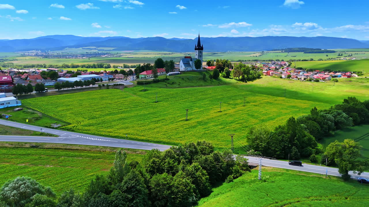 Countryside church and fields. Vast green fields surround a historic church in a picturesque village under a clear blue sky in early afternoon