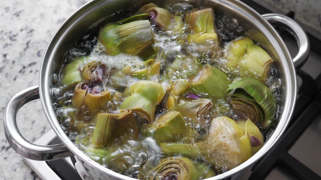 Boiling and cooking artichokes in saucepan, closeup