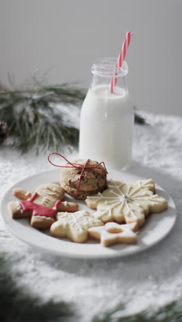 vertical video of bottle of milk, cookies with copy space on snow background