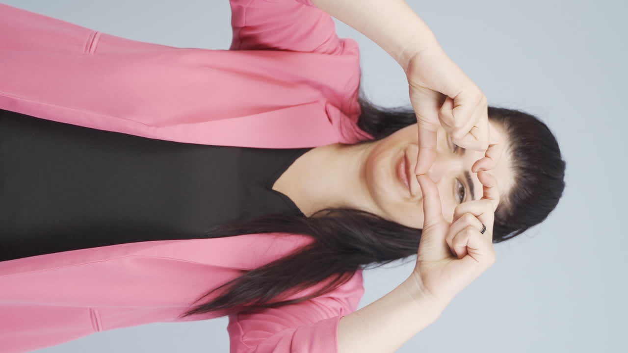 video vertical de una mujer de negocios haciendo corazón a la cámara.