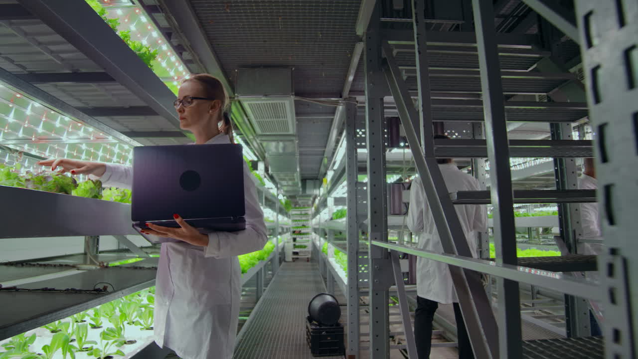 los científicos y los agricultores trabajan juntos en un equipo para crear plantas limpias en un entorno artificial utilizando computadoras portátiles y tabletas de tecnología moderna.