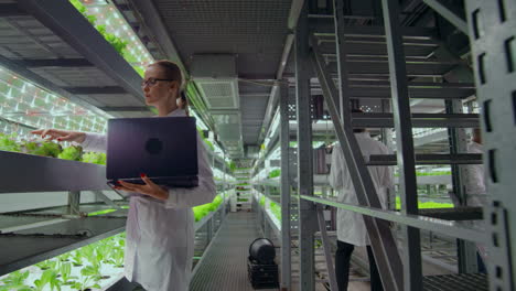 scientists and farmers work together in a team to create clean plants in an artificial environment using modern technology laptops and tablets.