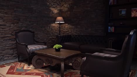 carpet on the floor of a rustic hotel's receiving room with simple wooden furniture and a brick wall