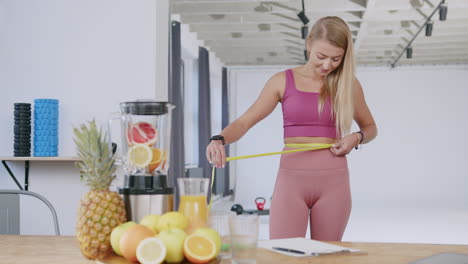 young fit athletic woman measuring her waist