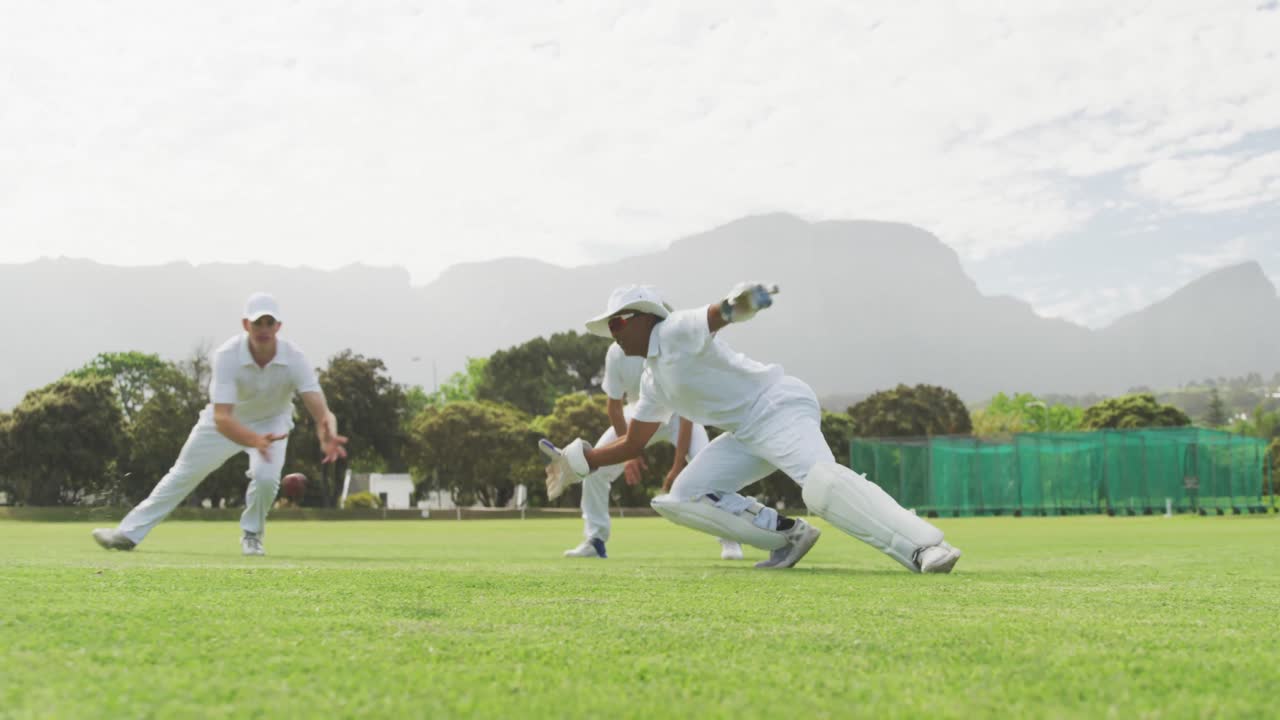 크리켓 선수 가 피치 에서 공 을 잡고 있다