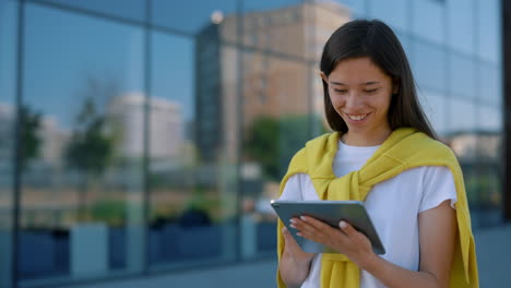 young woman using tablet outside modern building