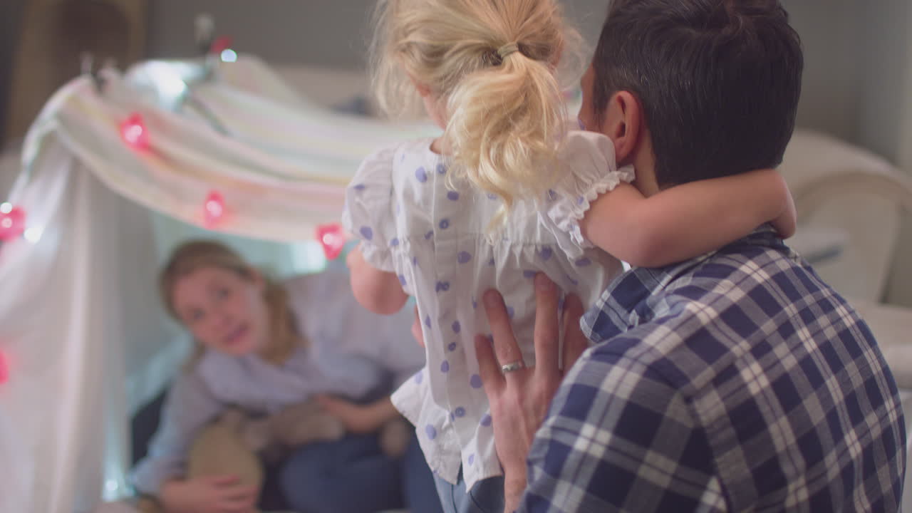 Laughing parents with young daughter having fun in homemade camp in child's bedroom at home - shot on slow motion