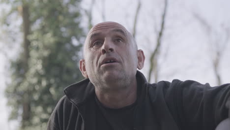 Albanian-Man-Speaking-And-Listening-To-Someone-While-Sitting-Outdoors-During-A-Sunny-Day---close-up,-static-shot