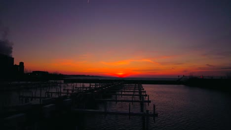 drone flying at low altitude over empty boat dock with beautiful sunset on the horizon