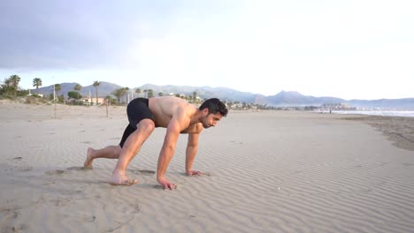 Hombre-Haciendo-Ejercicios-De-Suelo-Funcional-En-La-Arena-De-La-Playa-En-Cámara-Lenta