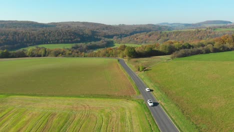 Weißes-Auto,-Das-Während-Der-Herbstfarben-Durch-Die-Malerische-Landschaft-Fährt