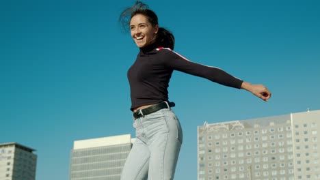 empoderada, feliz, joven y atractiva mujer latina hace un feliz salto ganador un día soleado en la ciudad tiro medio