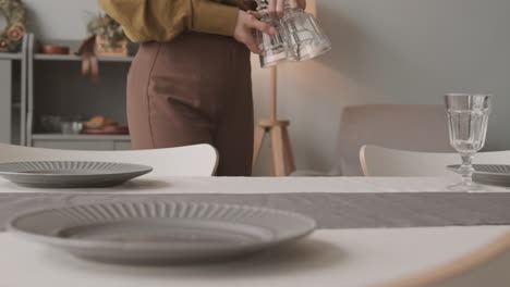 person arranging glasses on table