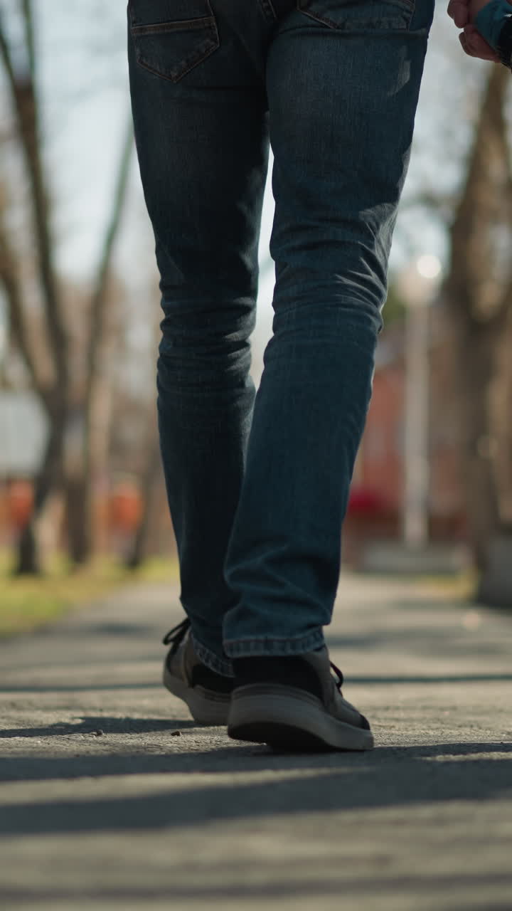 un primer plano de un padre y un hijo caminando de la mano en la acera, el adulto lleva pantalones vaqueros y botas, mientras que el niño está vestido con una chaqueta de cuero negra, pantalones vellos y botas