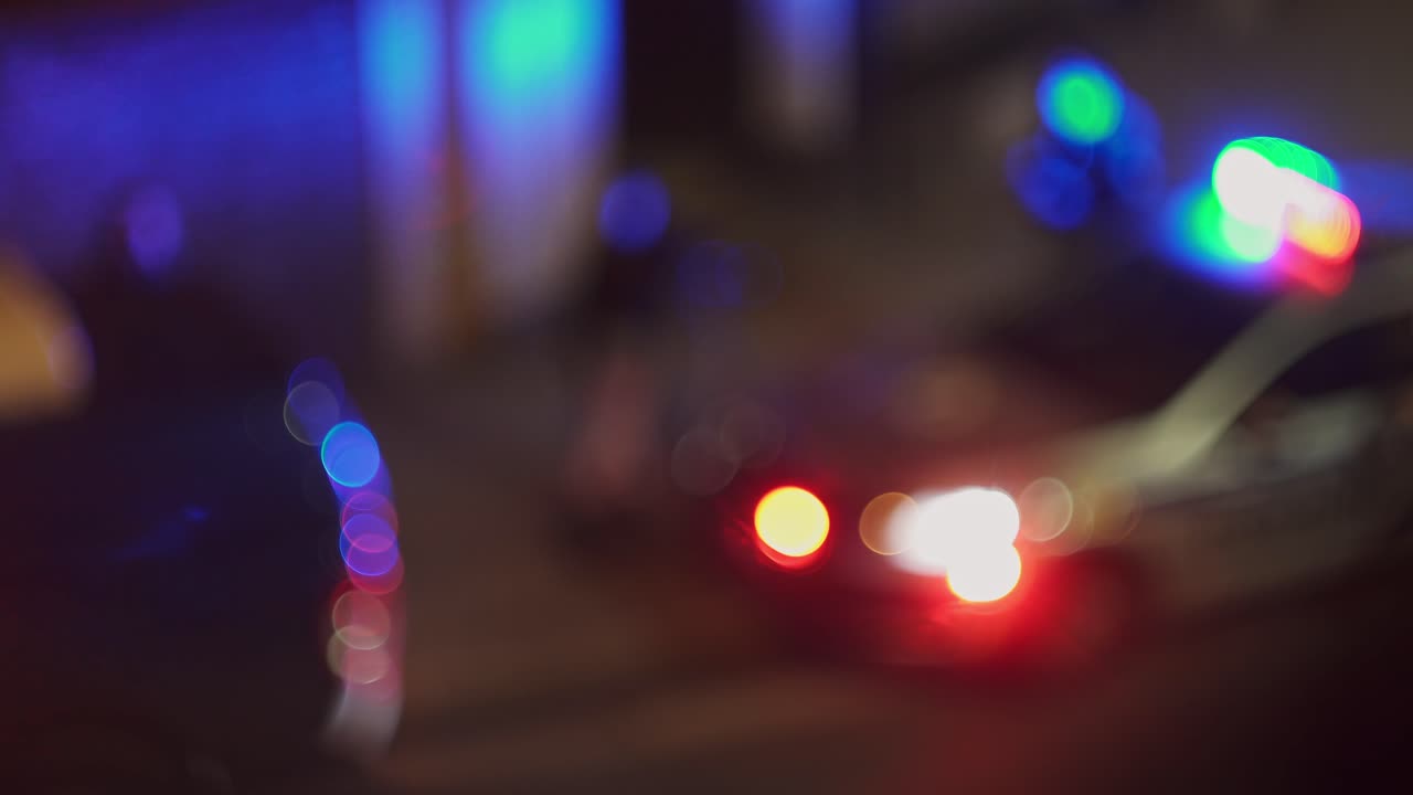 Flashing police car on street and policemen around, blurry bokeh night view
