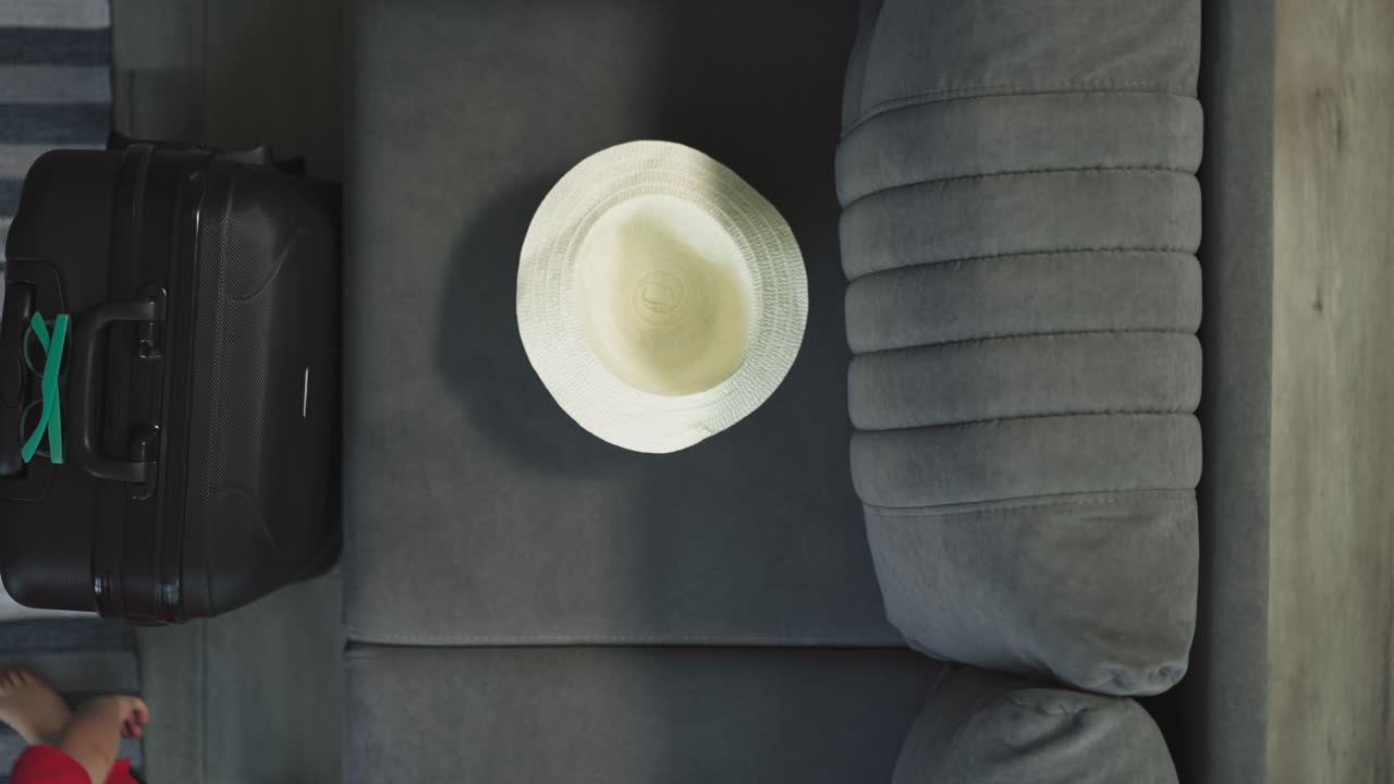 활동적 인 유아 는 가방 근처 의 부드러운 소파 에  ⁇  모자를 던진다