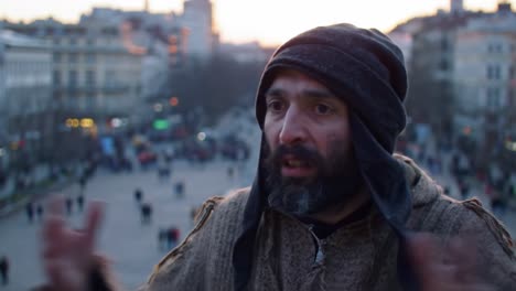 a man in traditional attire watches people on a bustling street as the sun sets. he shares insights about daily experiences and the vibrant city atmosphere amidst the crowd.