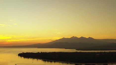 yellow sunset of a small island, a large body of water and mountains in popular holiday location of lombok, indonesia