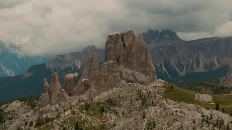 parallax drone shot massive rock formations with distant tall mountains in the background, green forest at the bottom, cloudy day, cinematic color grade