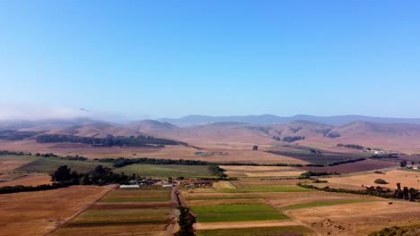 Drone-shot-over-farm-with-hills-and-low-cloud-in-the-background