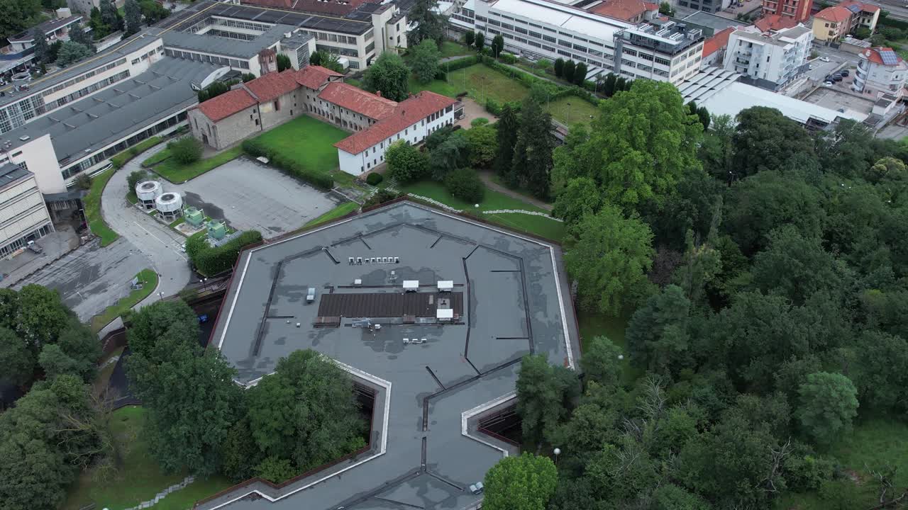 Top-down drone shot of Olivetti’s historic company canteen in Ivrea, designed to harmonize with nature, surrounded by dense forest, example of humane modernist industrial architecture, , slow motion