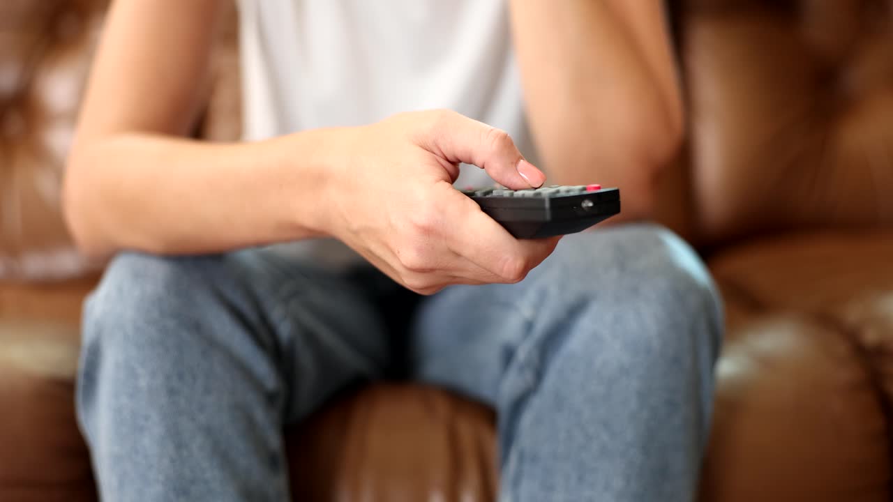 Telecomando TV nelle mani di una donna punta alla TV e la accende o spegne.
