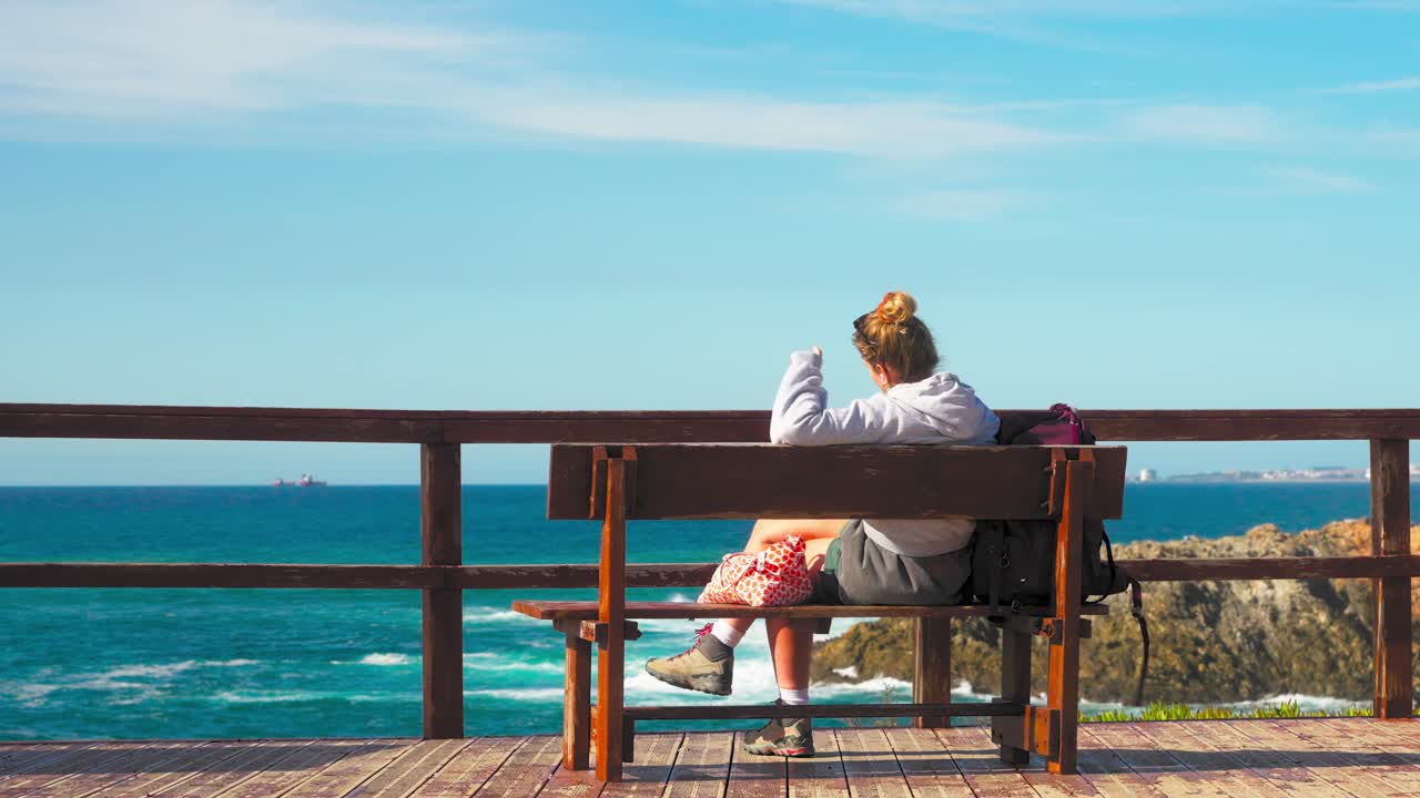 Woman sitting on a bench contemplating the coastal view