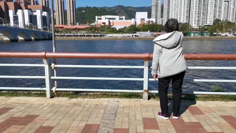 retired woman doing exercise in front of the sha tin shing mun river at hong kong