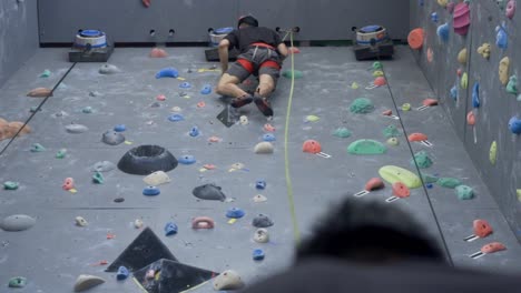 Asian-rock-climber-at-top-of-indoor-wall-in-gym