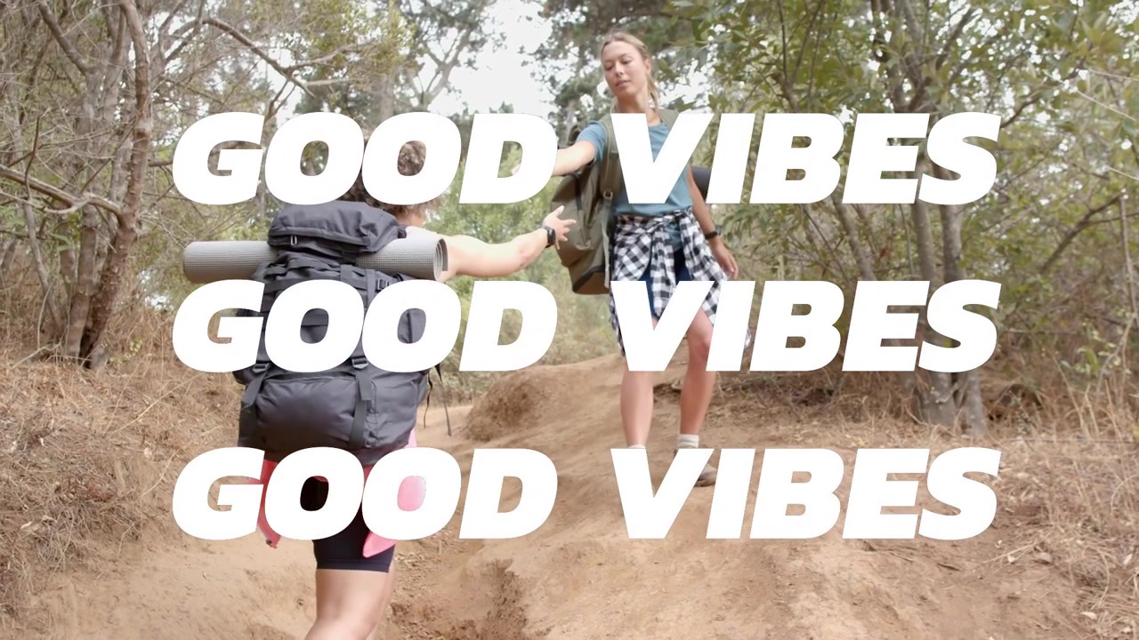To kvinner som går tur på en sti, en venn strekker ut en hånd, en klatrer trekker opp en sekk, med «GOOD VIBES» som glitsjer over rammen.