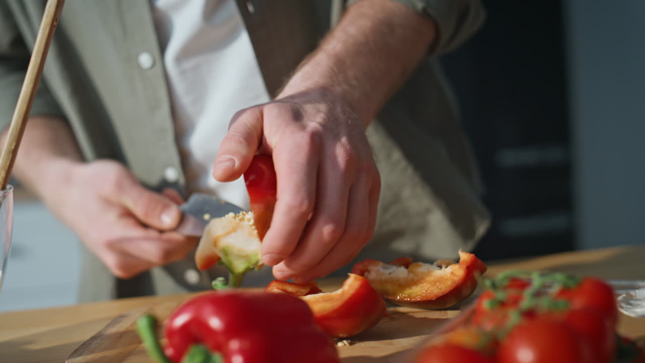 Man hands slicing pepper on kitchen closeup. Unknown guy preparing ingredients