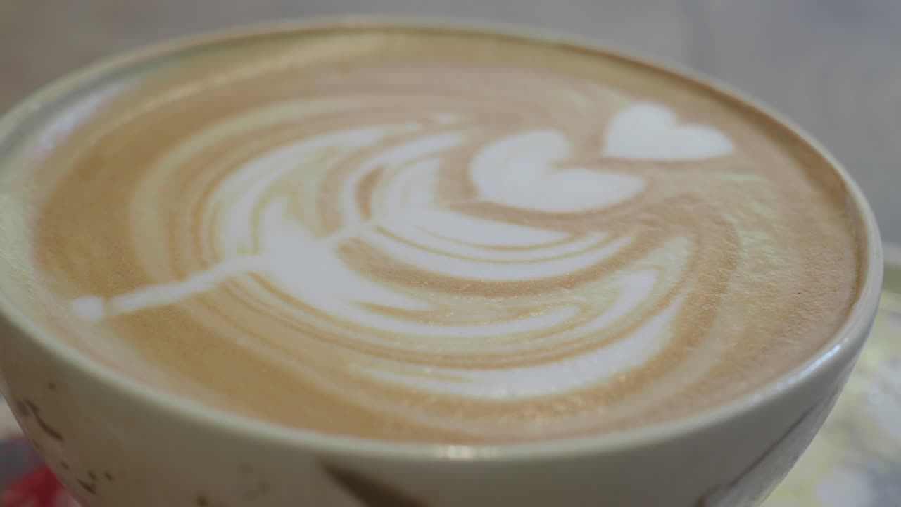 Primo piano di latte art con disegno a cuore in una tazza di caffè.