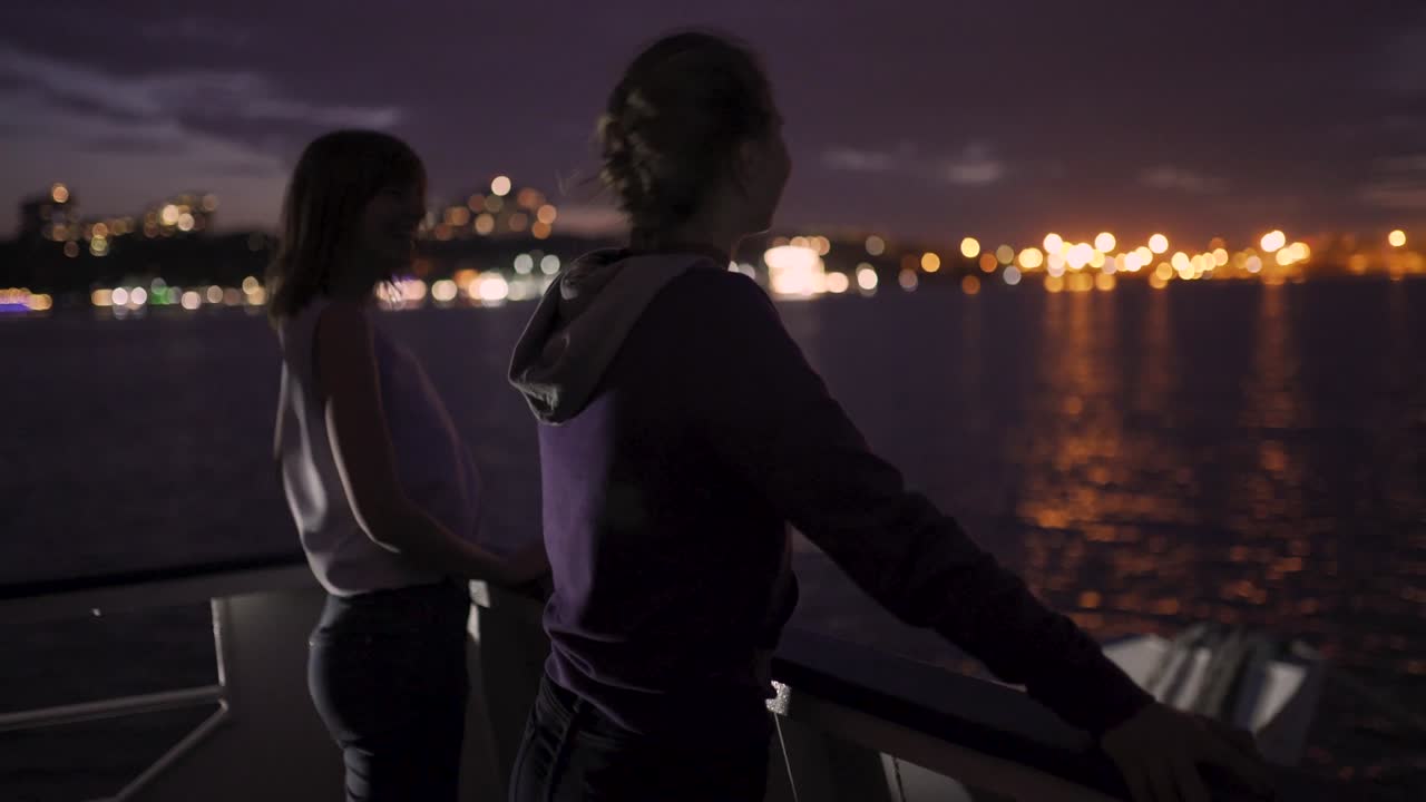 밤에 배를 타고 여행하는 두 명의 매력적인 젊은 여성의 실루.