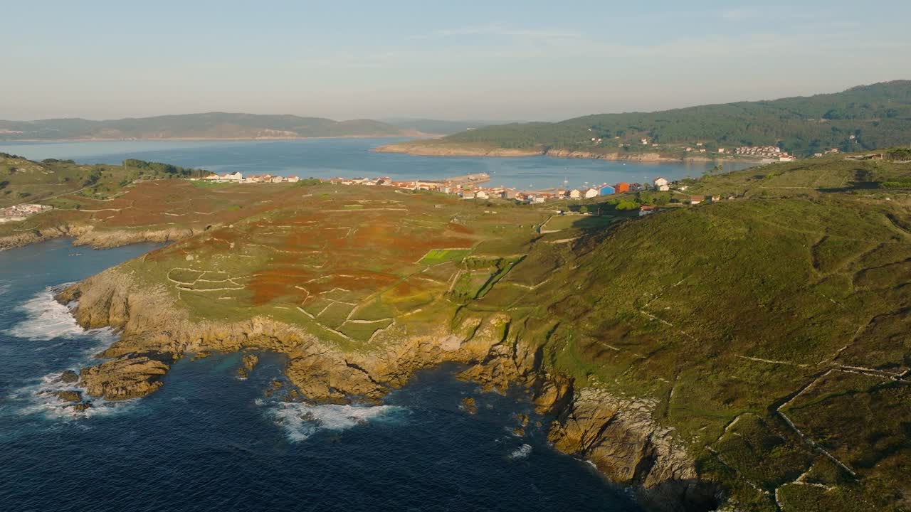 Luftaufnahme einer Felsmauer auf den Berghügeln mit Blick auf die Stadt und den Strand von Laxe in Spanien